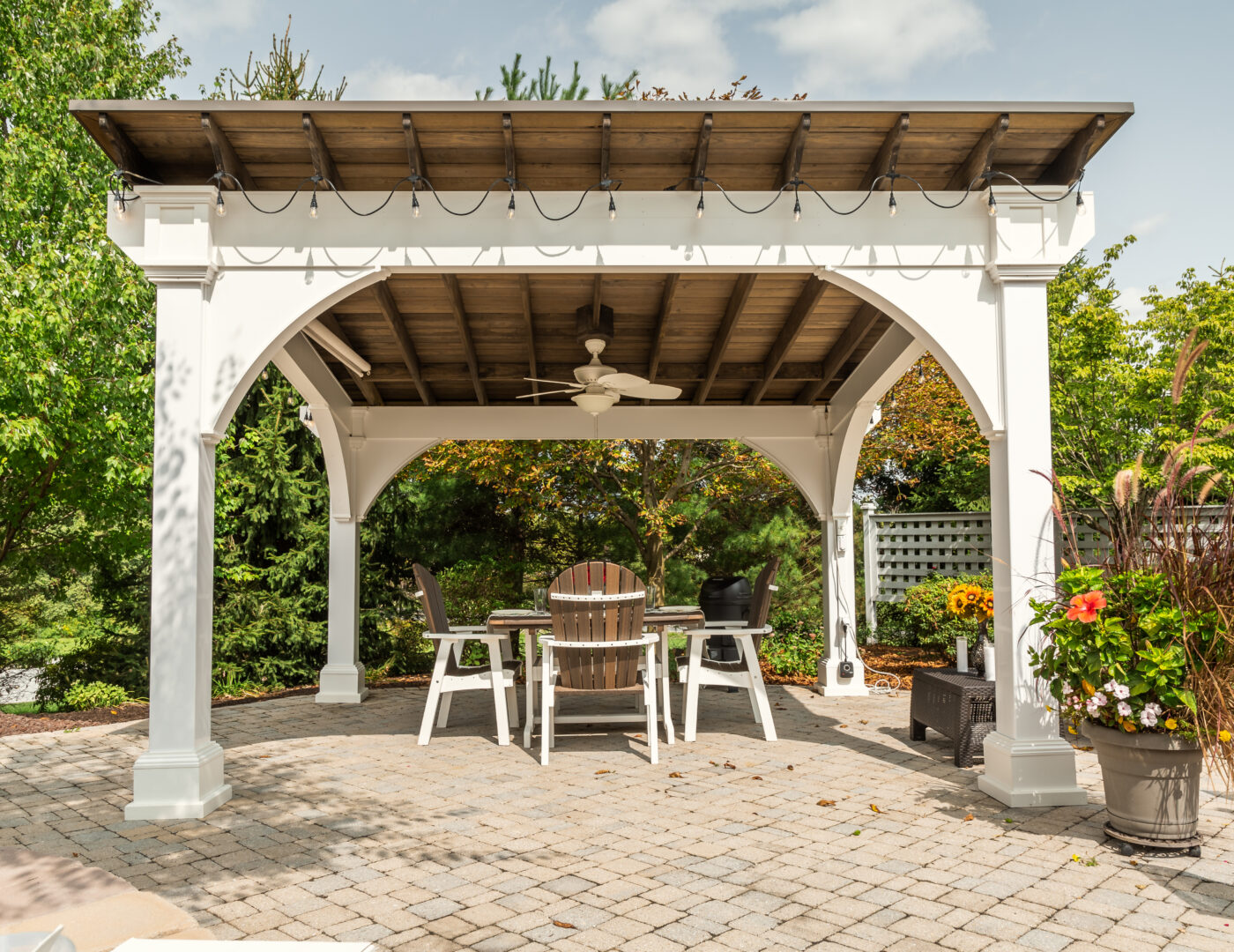 12x14 white Vinyl Santa Fe Pavilion on a back patio with a dining set.