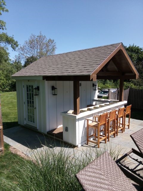 a frame cabana with white siding and brown roof, with a bar area