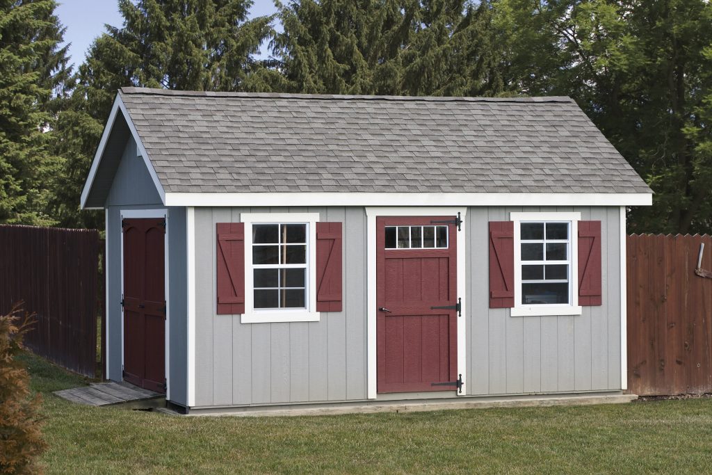 a frame shed with gray siding, white trim, and red doors and shutters