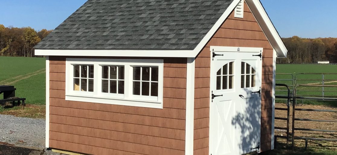 classic garden cottage shed with brown siding and white doors and windows