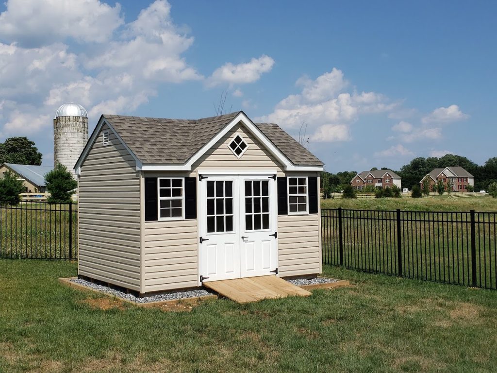 dormer shed with cream siding, white double doors, black shutters, and a ramp