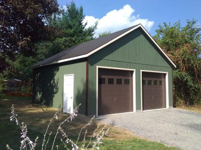 doublewide 2 story garage with green siding and brown garage doors